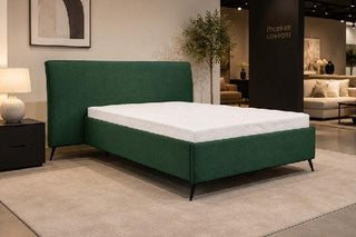Green bed frame with white mattress in a showroom setting