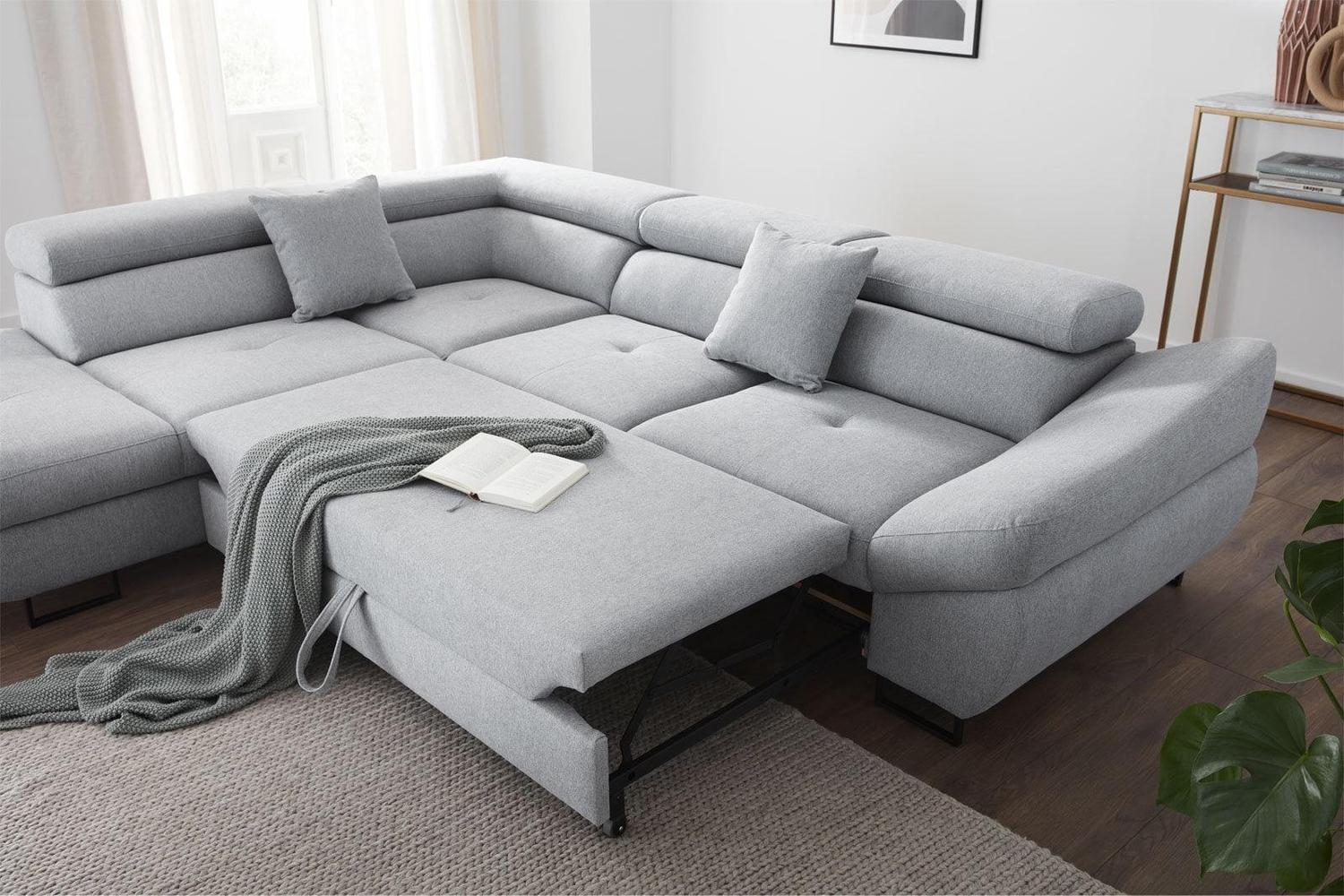 Gray sectional sofa in a living room setting with a blanket and book.