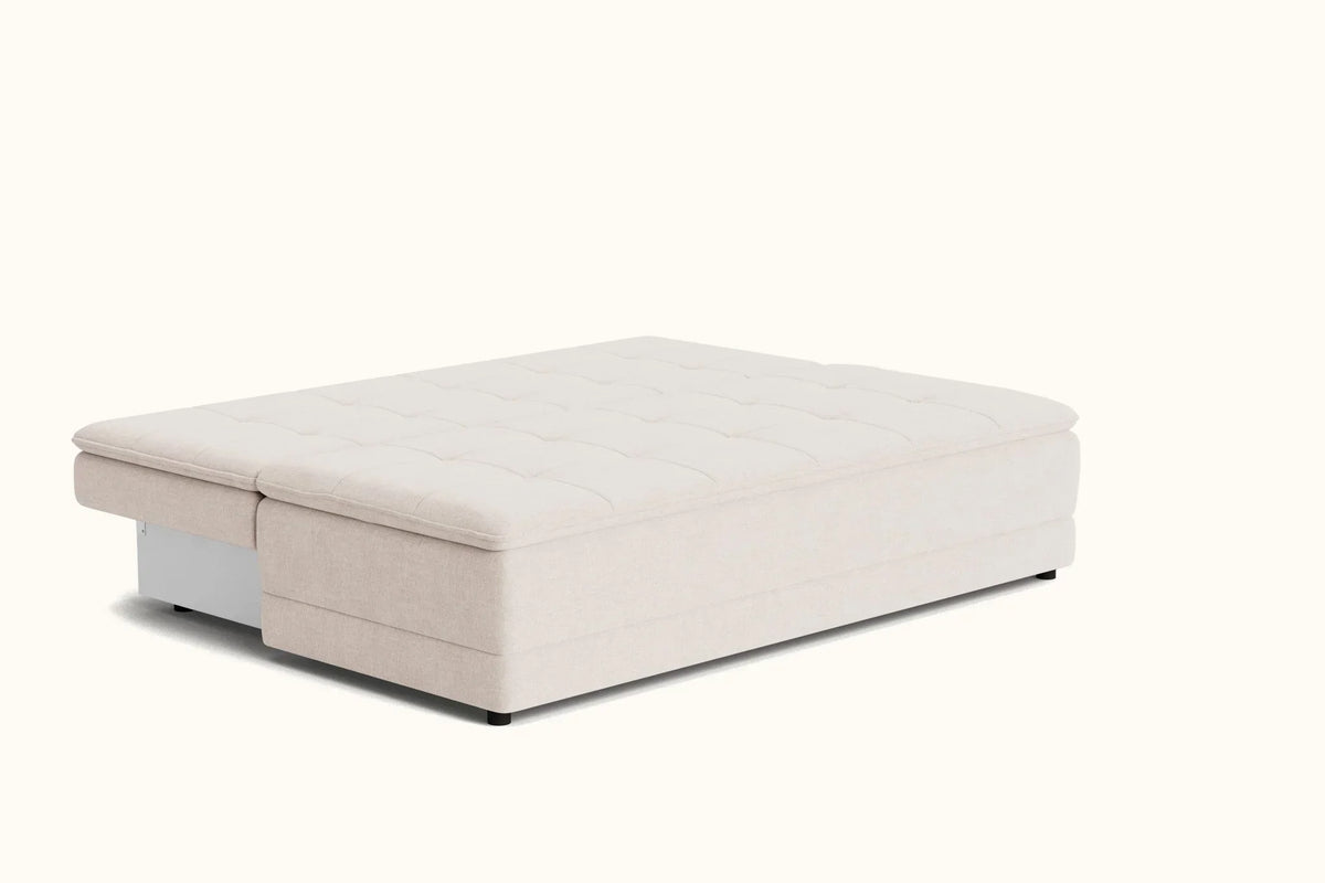 A modern upholstered ottoman or storage bench with a tufted top cushion, shown in a light beige fabric on a clean off-white background.