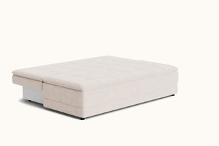 A modern upholstered ottoman or storage bench with a tufted top cushion, shown in a light beige fabric on a clean off-white background.