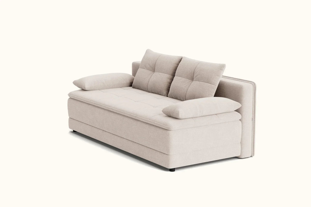A modern upholstered sofa bed in a light beige fabric, featuring a tufted backrest with two cushions, matching side bolsters, and two loose throw pillows, shown on a plain off-white background.