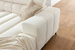 White sectional sofa with a textured pillow on a wooden floor