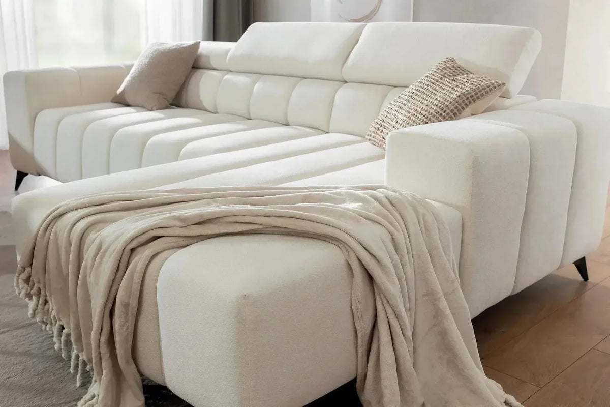 White sectional sofa with a blanket and pillows in a living room setting.