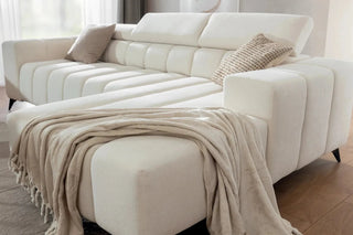 White sectional sofa with a blanket and pillows in a living room setting.